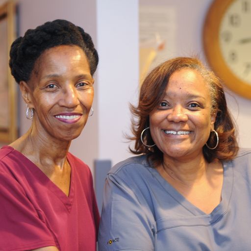 Two women standing next to each other in front of a clock.